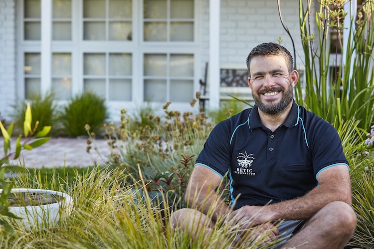 Luke sitting in a native garden in Perth with several species of native plants